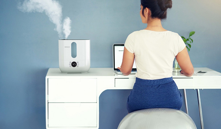 Женщина сидит за компьютером с увлажнителем воздуха